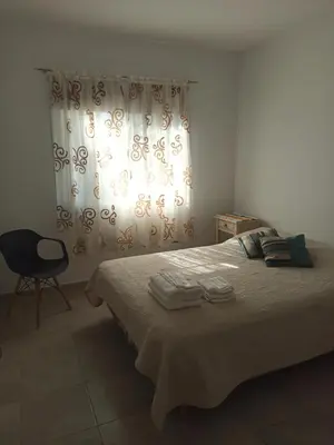 a bedroom with a bed and a chair and a window at Apartamento Alto Alberdi in Cordoba