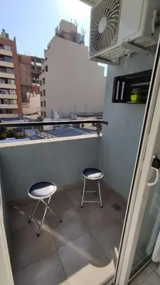 two stools on a balcony with a view of a city at DeRest - Barrio General Paz in Cordoba