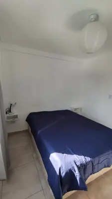 a bed in a white room with a blue blanket at DeRest - Barrio General Paz in Cordoba