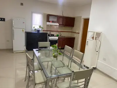 a kitchen with a glass table with chairs and a refrigerator at El Búho Apart in Villa Parque Siquiman
