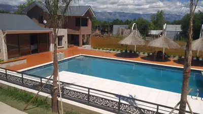 a swimming pool with umbrellas and a house at Apart Ladera Sur in Arroyo de Los Patos