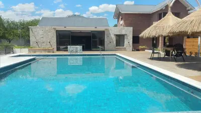 a swimming pool with blue water in front of a house at Apart Ladera Sur in Arroyo de Los Patos