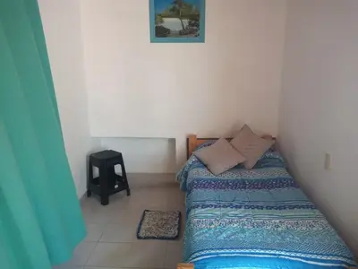 a small bedroom with a bed and a black stool at Casa Bela in Villa Carlos Paz