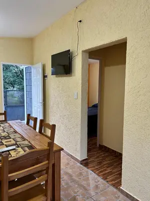 a dining room with a table and a tv on the wall at La casita de Oli in Tanti