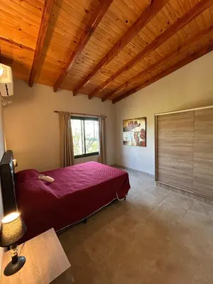 a bedroom with a red bed and a window at Refugio de las nubes in Las Rabonas