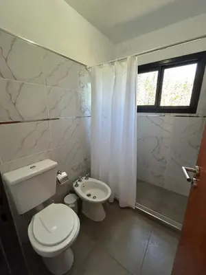 a white bathroom with a toilet and a shower at Refugio de las nubes in Las Rabonas