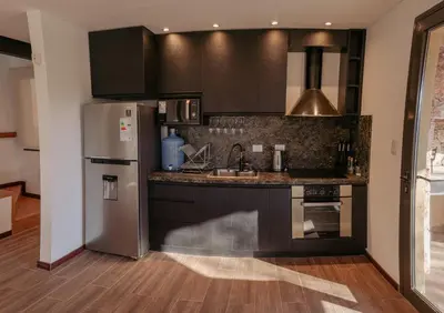 a kitchen with black cabinets and a stainless steel refrigerator at Cabañas Las Marias - Mirador del Lago in Villa Parque Siquiman