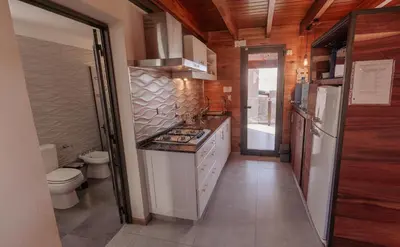 a small kitchen with a stove and a toilet at Cabañas Las Marias - Mirador del Lago in Villa Parque Siquiman
