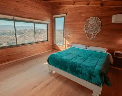 a bedroom with a bed with wooden walls and windows at Cabañas Las Marias - Mirador del Lago in Villa Parque Siquiman
