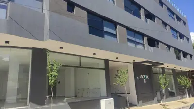 a building with glass windows and trees in front of it at Departamento Premium Aqua II in Villa Carlos Paz