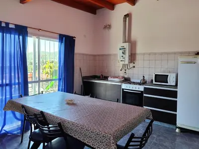a kitchen with a table with chairs and a microwave at Complejo Gabriel - Departamentos Temporarios in Villa Carlos Paz