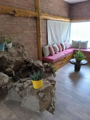 a living room with a pink couch and a stone fireplace at Casa montaña & jacuzzi in Embalse