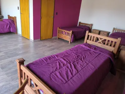 a room with three beds with purple blankets at Casa montaña & jacuzzi in Embalse