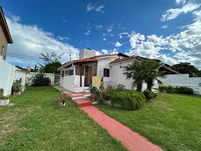 a small white house with a grass yard at Casa Jazmín in Villa Carlos Paz