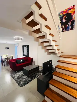 a living room with a staircase and a red couch at Duplex temporario en Villa Carlos Paz in Villa Carlos Paz