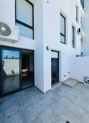 a white building with glass doors and a patio at Duplex temporario en Villa Carlos Paz in Villa Carlos Paz