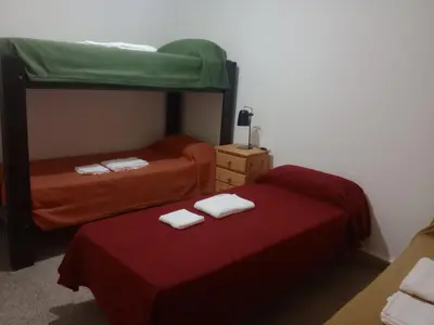a bedroom with two bunk beds with red sheets at El Quebrachito in Alta Gracia