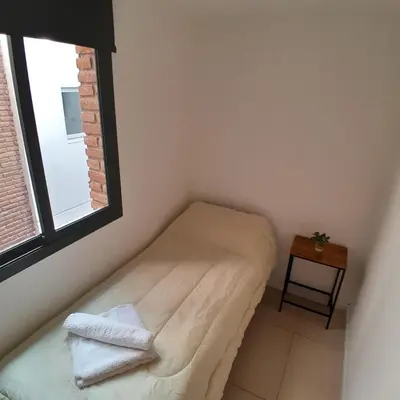 a small bedroom with a bed and a window at Departamento temporal in Cordoba