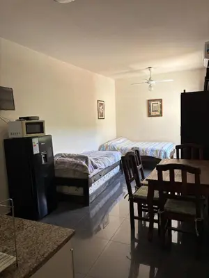 a room with two beds and a table and chairs at Dpto monoambiente in Villa Carlos Paz