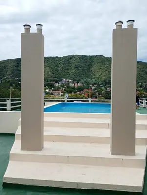 a dock with two columns and a swimming pool at Dpto monoambiente in Villa Carlos Paz