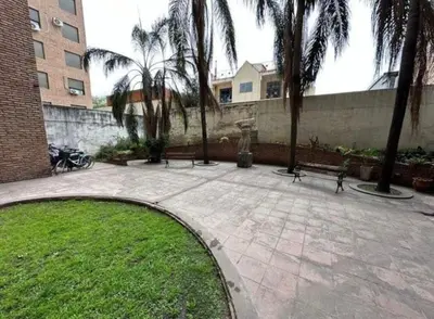 a park with benches and palm trees and a building at Depto en Güemes in Cordoba
