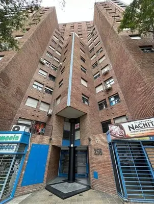 a tall brick building with blue doors and windows at Depto en Güemes in Cordoba
