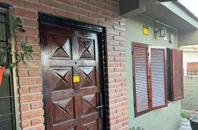 a brick wall with a wooden door and a window at Chalet LA BERNI in Villa Carlos Paz