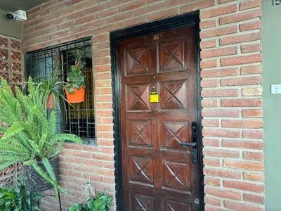 a brick building with a brown door and a window at Chalet LA BERNI in Villa Carlos Paz