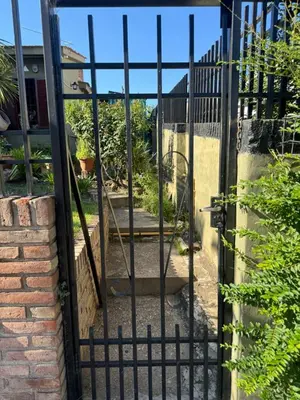 an open gate to a garden with a patio at Chalet LA BERNI in Villa Carlos Paz