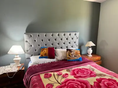 a bedroom with a bed with a purple comforter and roses at Chalet LA BERNI in Villa Carlos Paz