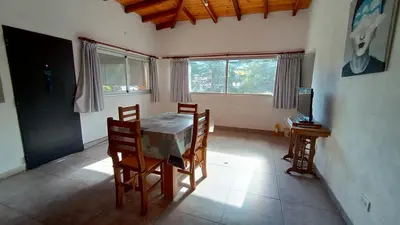 a dining room with a table and chairs and windows at Departamento España in Santa Rosa de Calamuchita