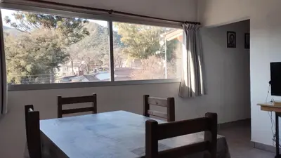 a dining room with a table and a large window at Departamento España in Santa Rosa de Calamuchita