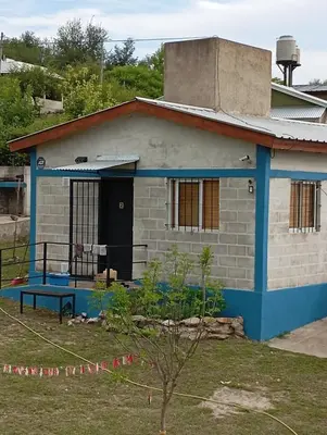 a blue and white house with a dog in the doorway at Villacumbreazul in Cuesta Blanca