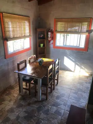 a dining room with a wooden table and some windows at Villacumbreazul in Cuesta Blanca