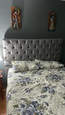 a bed with a gray headboard with blue flowers on it at Chalet BERNI in Villa Carlos Paz