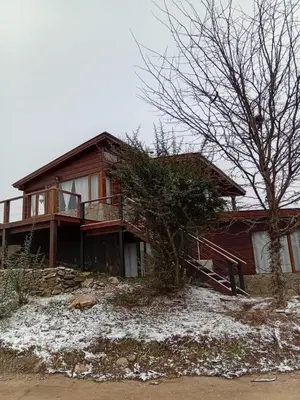 a house with snow on the ground in front of it at Medio Cielo Cabaña de Montaña in Rincón de Luna