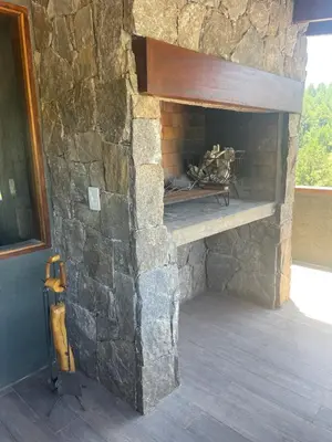 a stone fireplace with a wooden shelf in a room at Medio Cielo Cabaña de Montaña in Rincón de Luna
