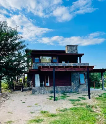 a stone house with a balcony on top of it at Medio Cielo Cabaña de Montaña in Rincón de Luna