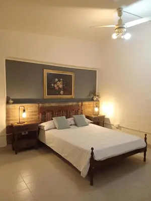 a bedroom with a large bed with two tables and a painting at Refugios del Alma 24 in Villa de Las Rosas