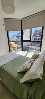 a bedroom with a bed with a large window at Dpto zona GRAL PAZ a cuadras de la Clínica Reina Fabiola in Cordoba