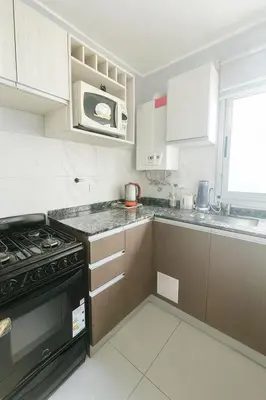 a kitchen with a stove and a microwave at Depto Elegante, Centrico, Calef Central, Cochera in Villa Carlos Paz