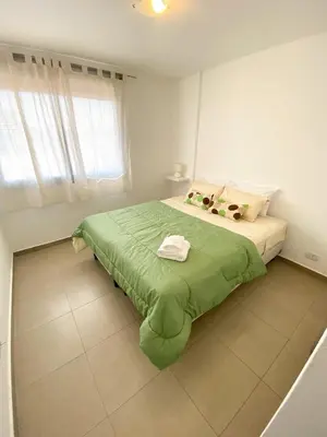 a bedroom with a bed with a green blanket at LitStay Montevideo in Cordoba