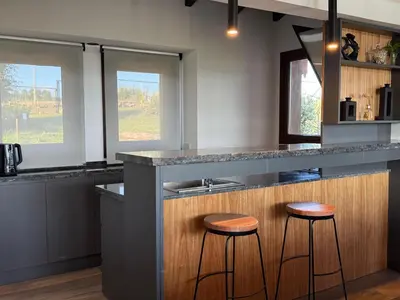 a kitchen with two bar stools and a sink at Altos de Cumbrecita - Casa Suite in La Cumbrecita