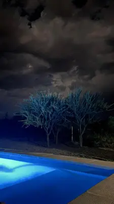 two trees with blue lighting in front of a cloudy sky at Casa Las Breas del Champaquí in Las Tapias