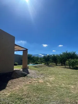 a field with a building and trees in the background at Casa Las Breas del Champaquí in Las Tapias