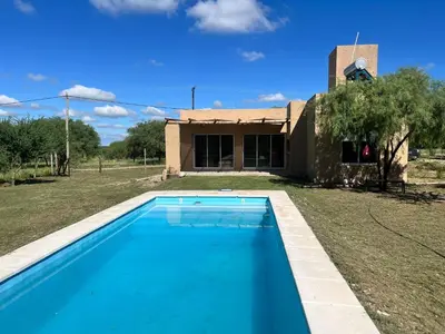 a blue swimming pool in front of a house at Casa Las Breas del Champaquí in Las Tapias