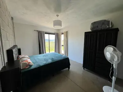 a bedroom with a bed and a window with a fan at El Descanso in San Roque