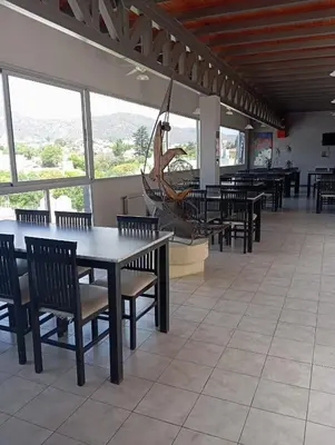 a dining room with tables and chairs and windows at Dpto 1 dormitorio céntrico piscina cochera in Villa Carlos Paz