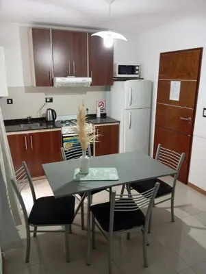 a kitchen with a table and chairs in a kitchen at Dpto 1 dormitorio céntrico piscina cochera in Villa Carlos Paz