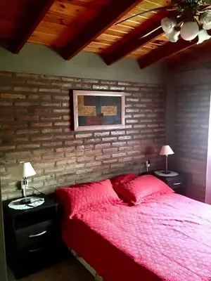 a bedroom with a red bed and two night stands with lamps at ovidio and Elda's house in Villa Carlos Paz